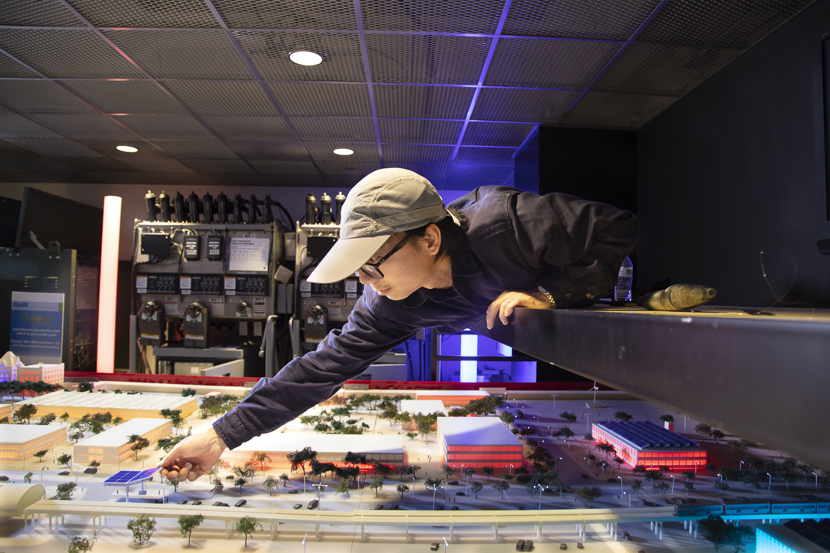 A graduate student adjusts a model of a microgrid in the WISER lab