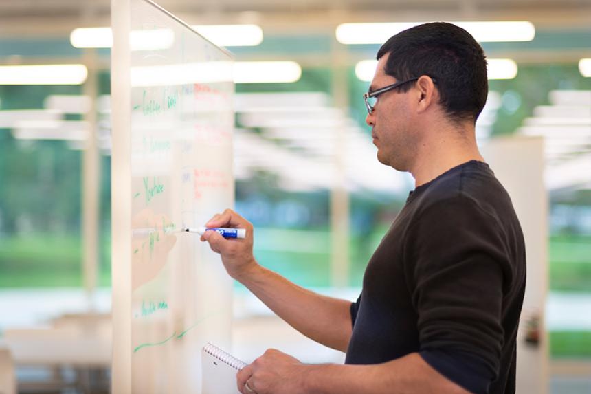 Faculty member writing on a white board for an IPRO class