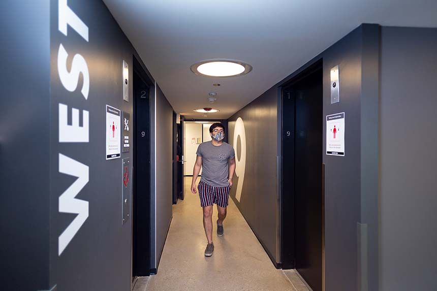 Kacek Hall Male Student in the hallway wearing a mask