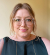 headshot of Amanda Stilwell with clear glasses and a green dress