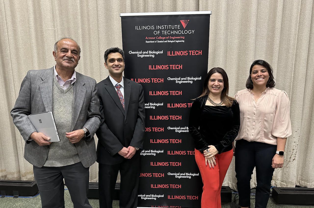 Photo of Sohail Murad, Mudassir Rashid, Julia Mazzoni Duarte, and Juliana Gomes de Guimarães in front of Illinois Tech banner