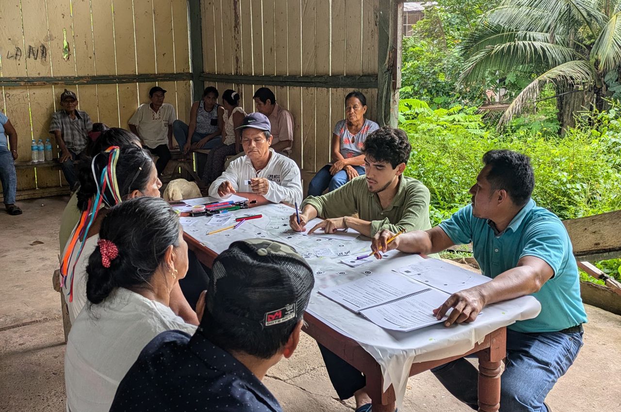 Kevin Malca, the Illinois Institute of Technology College of Architecture's 2025 Rowe Fellow, center in green shirt, maps terrain with an indigenous community in the Amazon rainforest