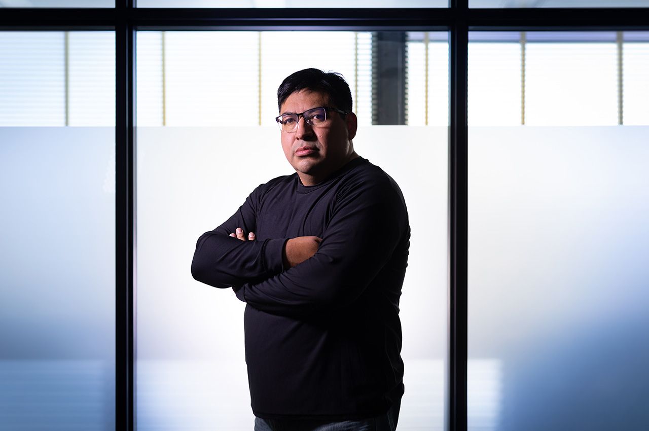 Photo of Illinois Tech Associate Professor of Biology Oscar Juarez in front of a glass window with his arms folded.