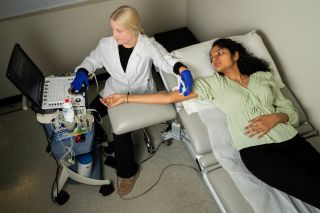 A student in the pre health program examines another student in a medical style setting