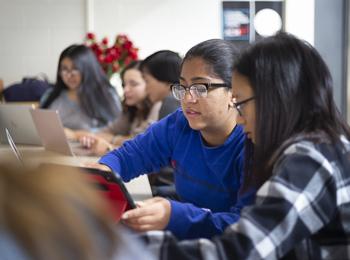 Two women work together to review programming