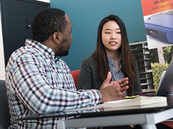 Two students talking at a desk