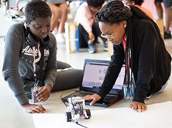 two pre collegiate students on floor with robot