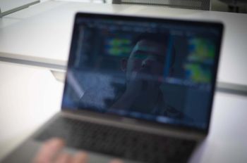 Student's reflection in laptop as he works