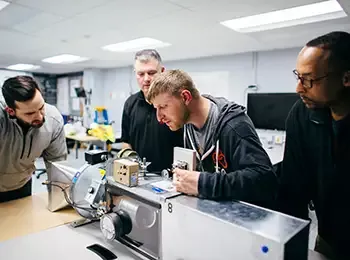 four students working on device in a lab