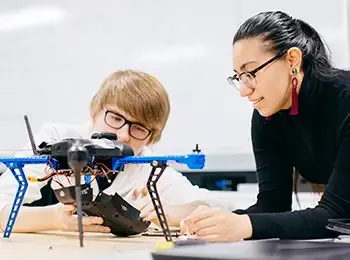 two people looking at a drone on a table