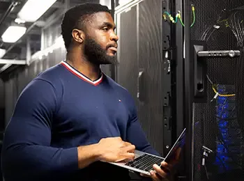 man with laptop looking at a server rack