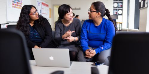 Photo of professor and students sitting together with a computer