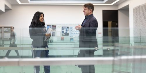 A political science professor chats with a student before class