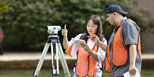 Two students survey a plot of land during a civil engineering class