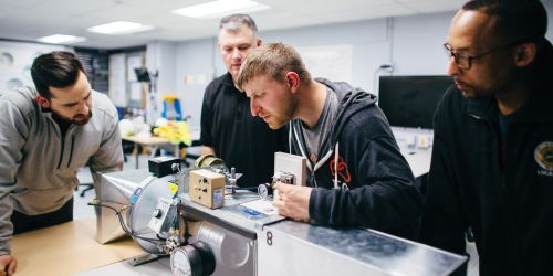 Students collaborating around a machine