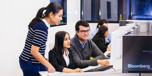 Multiple students working together on a computer in a computer lab