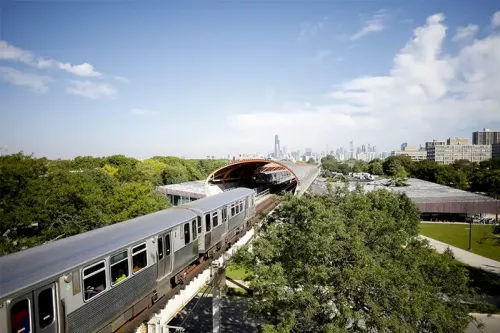 A green line train enters the tube above MTCC.