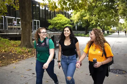 Three students walk down the main stretch of campus