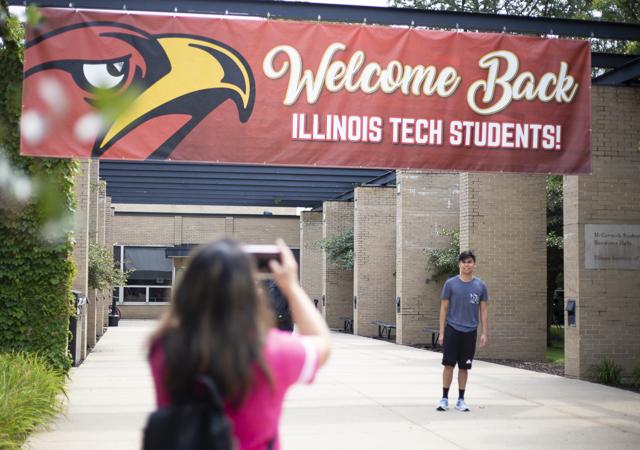 A student has his picture taken under a banner during move-in day