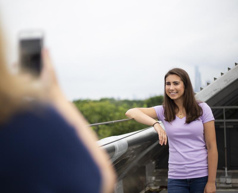 A student has her parent take her picture on the roof of SSV