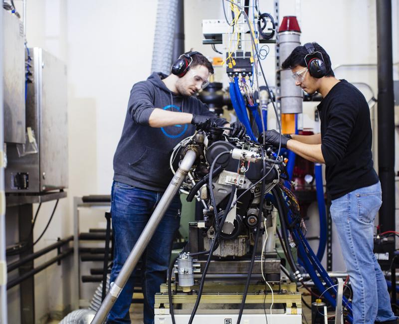 Two students work on an engine at Armour College of Engineering