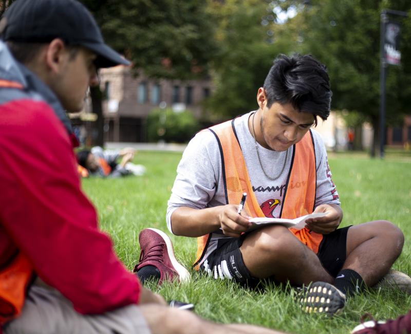 A student takes notes while surveying a plot of land