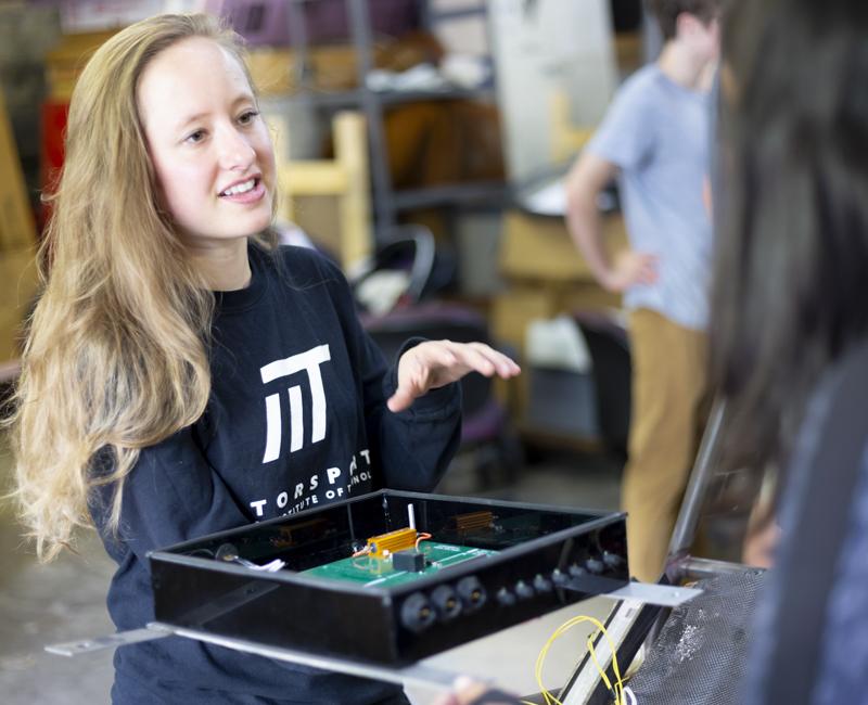 A member of the motorsports club explains the mechanics of a car to another student