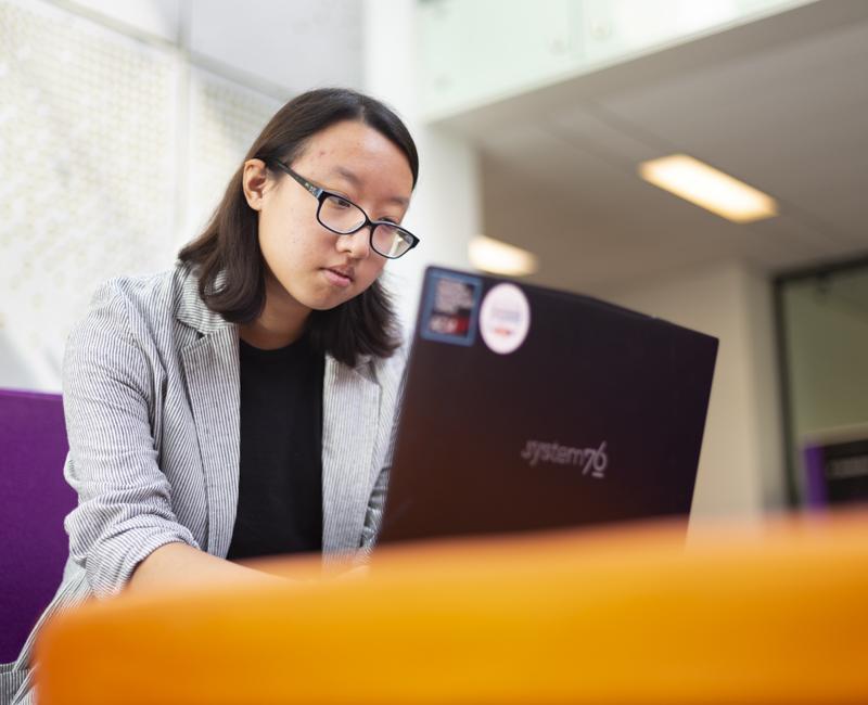 Anna Kong does data work on her laptop in the Retaliatta Atrium