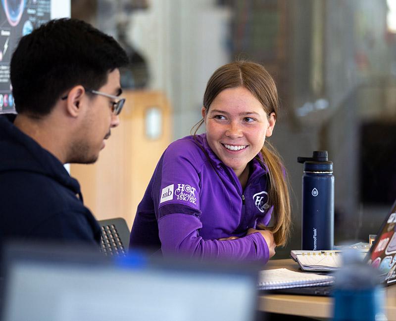 Two undergraduate students talking at a table.