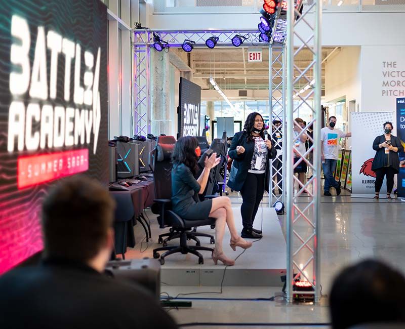 Two Illinois Tech staff members speaking on stage at an esports event.