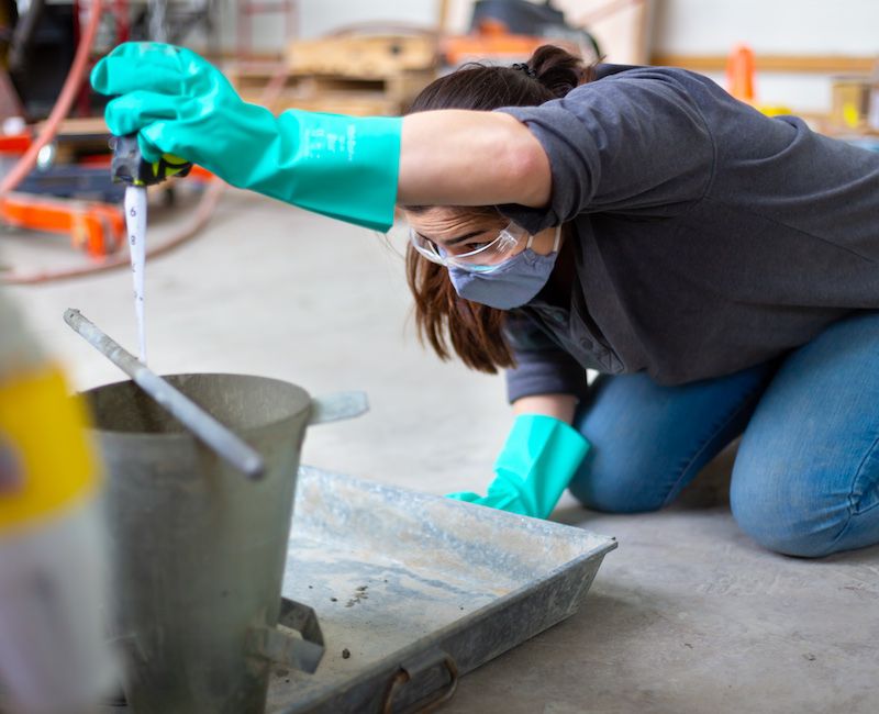 Student measuring concrete bucket in laboratory